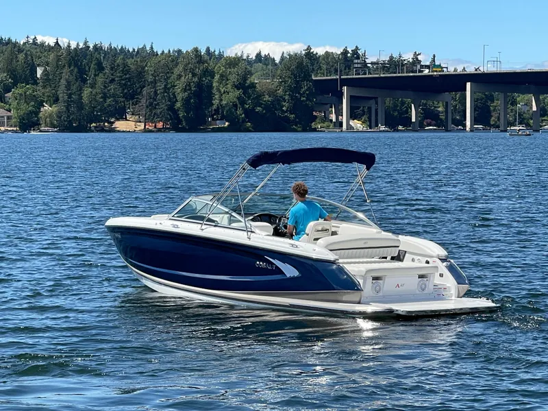 Slide: The Image of 2011 Cobalt A25 boat cruising on a scenic lake with a bridge in the background. - 8