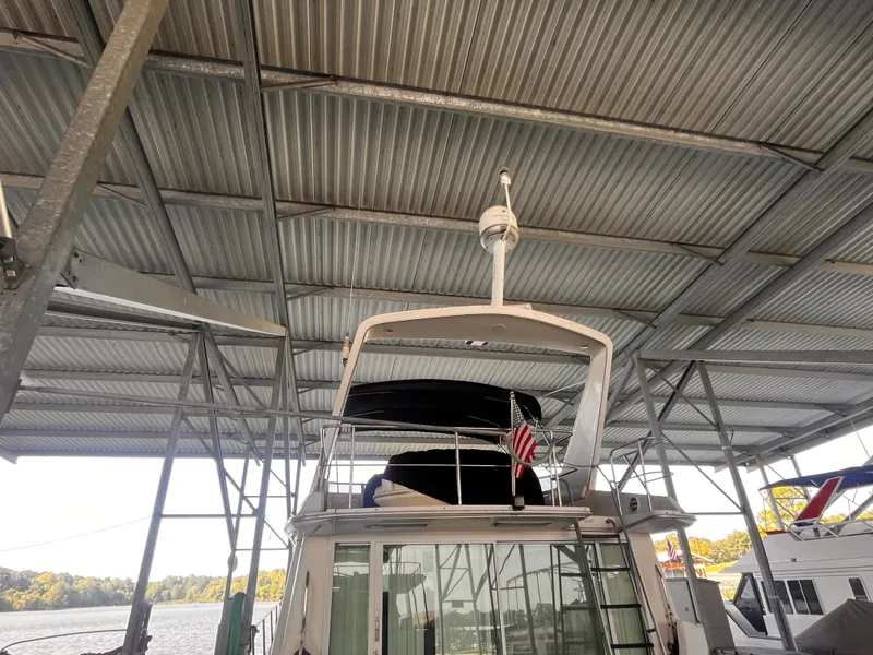 Slide: The Image of 1990 Sea Ray Sedan Bridge 500 docked under metal roof with American flag. - 5