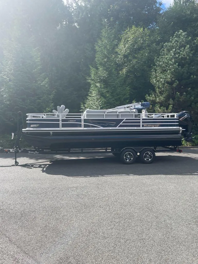 The Image of 2024 Ranger Reata 220F pontoon boat on trailer, parked outdoors. - 0