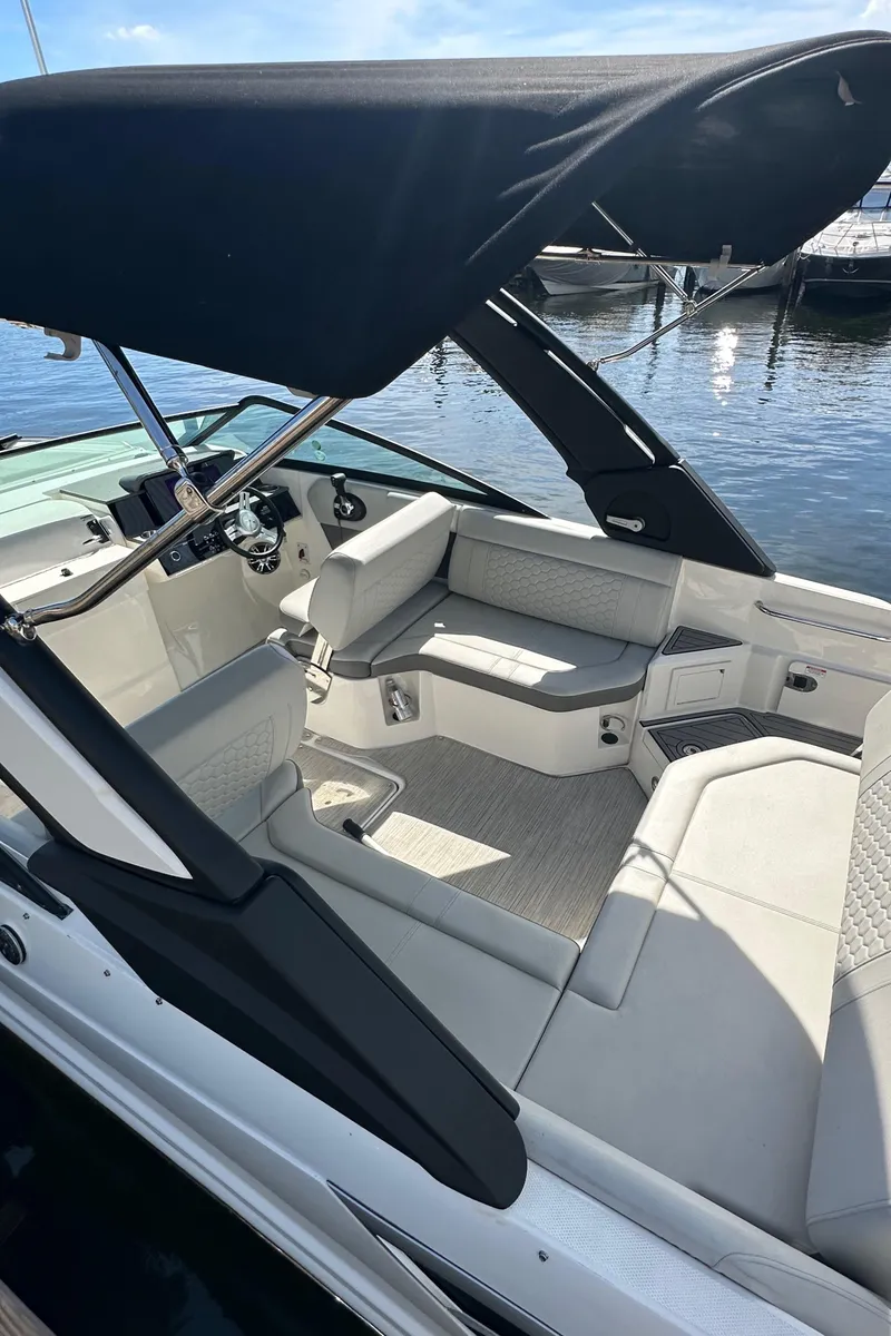 Slide: The Image of 2022 Sea Ray SDX 250 boat interior with seating and canopy, docked by the water. - 13