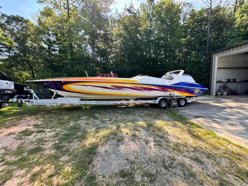 Slide: The Image of 1990 Fountain 42 Lightning speedboat on trailer, parked outdoors near trees. - 0