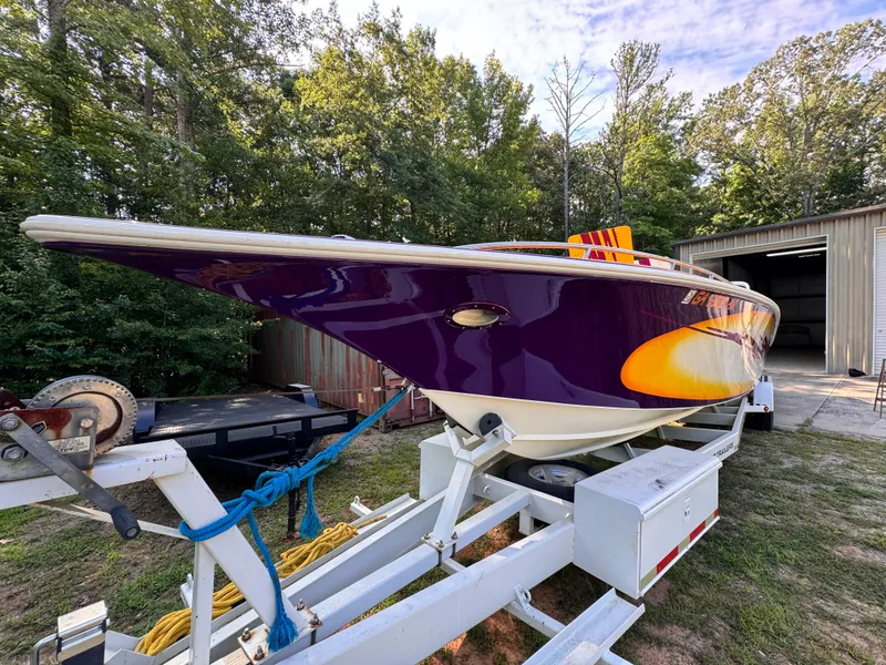 Slide: The Image of 1990 Fountain 42 Lightning speedboat on trailer, vibrant purple and yellow design, parked outdoors. - 11