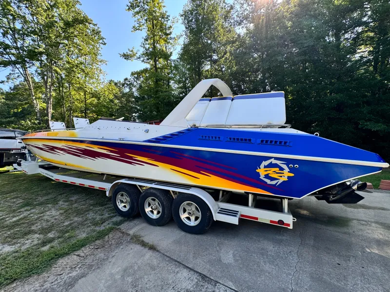 Slide: The Image of 1990 Fountain 42 Lightning speedboat with vibrant graphics on a trailer, surrounded by trees. - 2