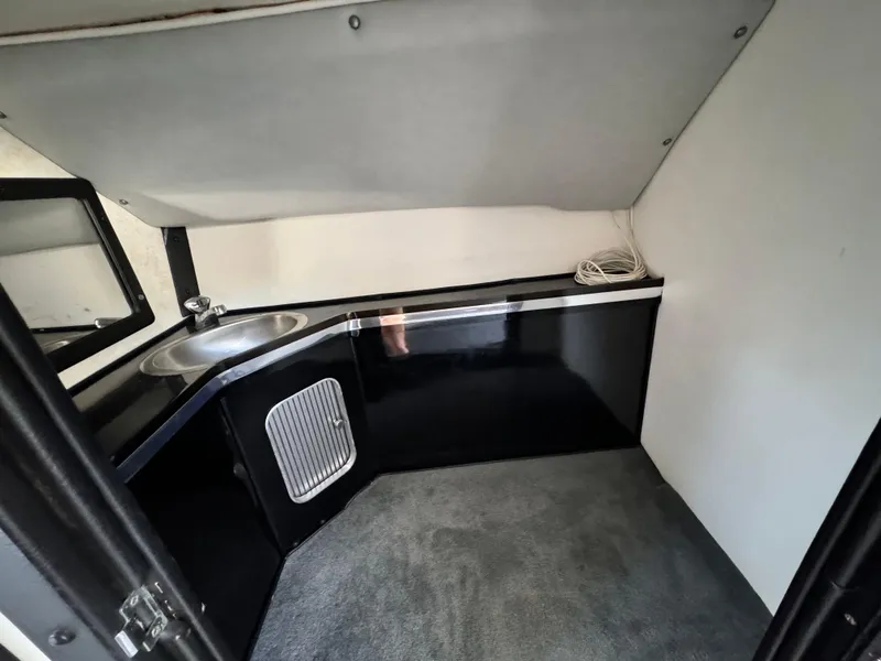 Slide: The Image of Interior of a 1990 Fountain 42 Lightning boat, featuring a compact kitchenette with sink. - 34