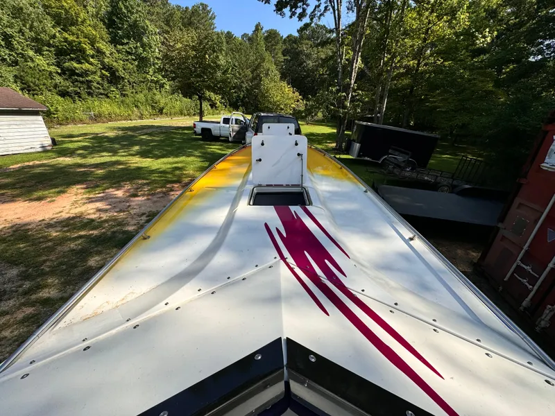 Slide: The Image of 1990 Fountain 42 Lightning boat with vibrant graphics, parked outdoors near trees and vehicles. - 40