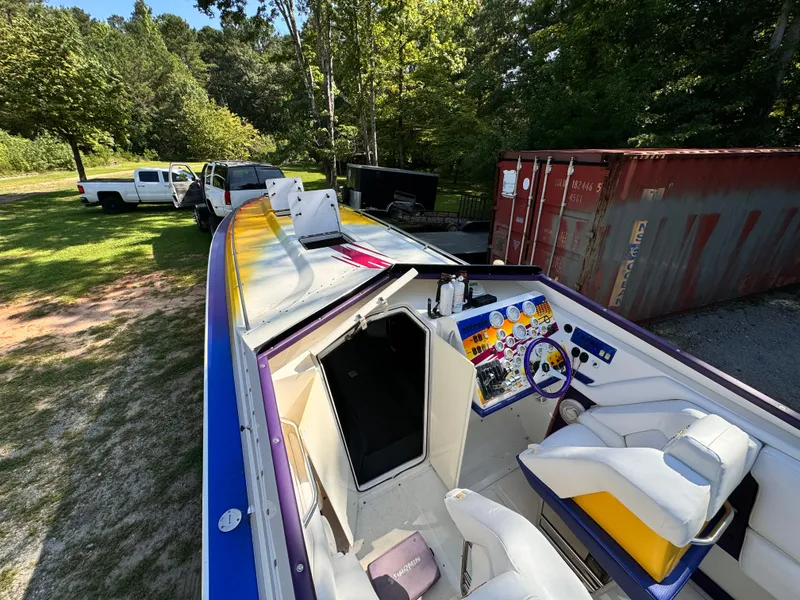 Slide: The Image of 1990 Fountain 42 Lightning boat with vibrant interior, parked outdoors near trees and vehicles. - 46