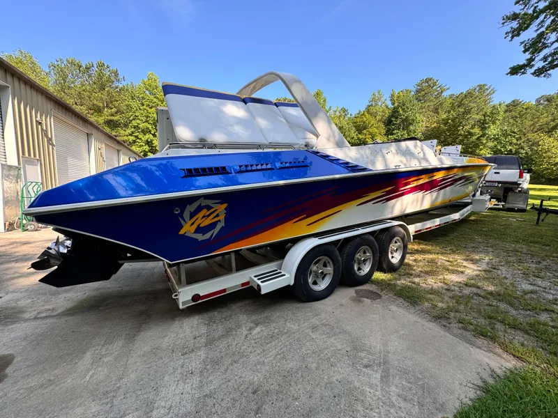 Slide: The Image of 1990 Fountain 42 Lightning speedboat on trailer, vibrant blue and yellow design, parked outdoors. - 6