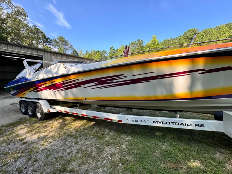 Slide: The Image of 1990 Fountain 42 Lightning speedboat on Myco trailer, vibrant graphics, parked outdoors. - 8