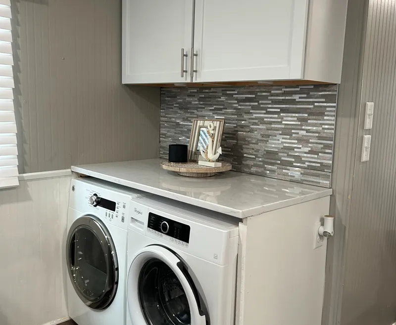 Slide: The Image of Laundry area with modern washer, dryer, and stylish backsplash on a 2004 Majestic Houseboat. - 23