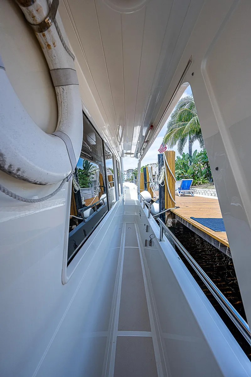 Slide: The Image of Side deck view of 2000 Offshore Yachts 62 Pilot House, docked with palm trees visible. - 15