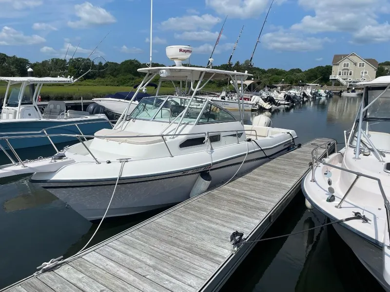 Slide: The Image of 2000 Grady-White 232 Gulfstream WA boat docked in a marina under a blue sky. - 2