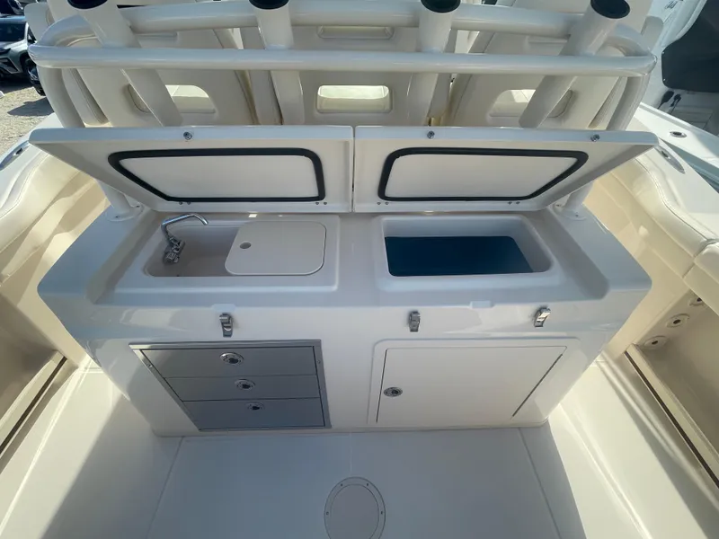 Slide: The Image of 2025 Grady-White Canyon 326 boat interior with open storage compartments and sink. - 10