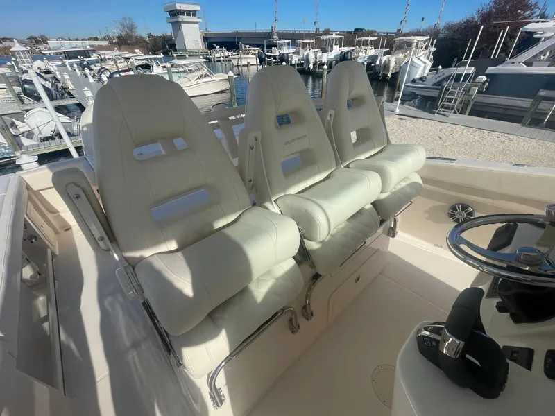 Slide: The Image of 2025 Grady-White Canyon 326 boat seats at marina, featuring luxurious white upholstery. - 8