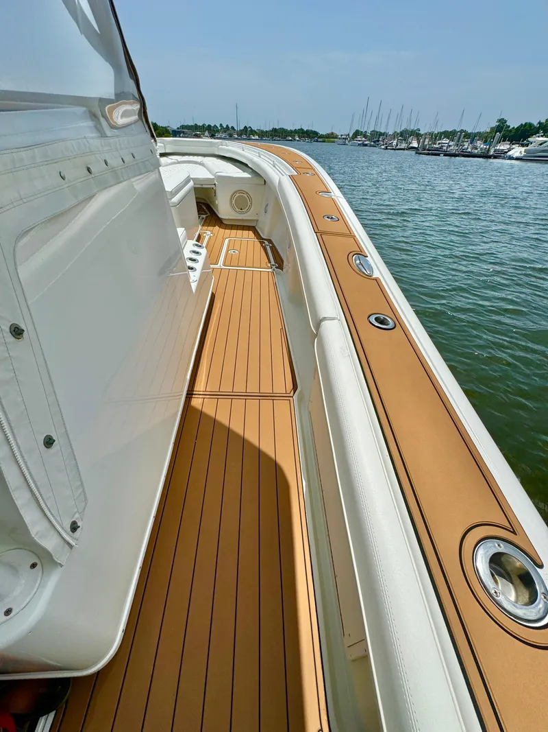 Slide: The Image of 2012 Yellowfin 39 Open boat deck with teak flooring, docked by the water. - 20