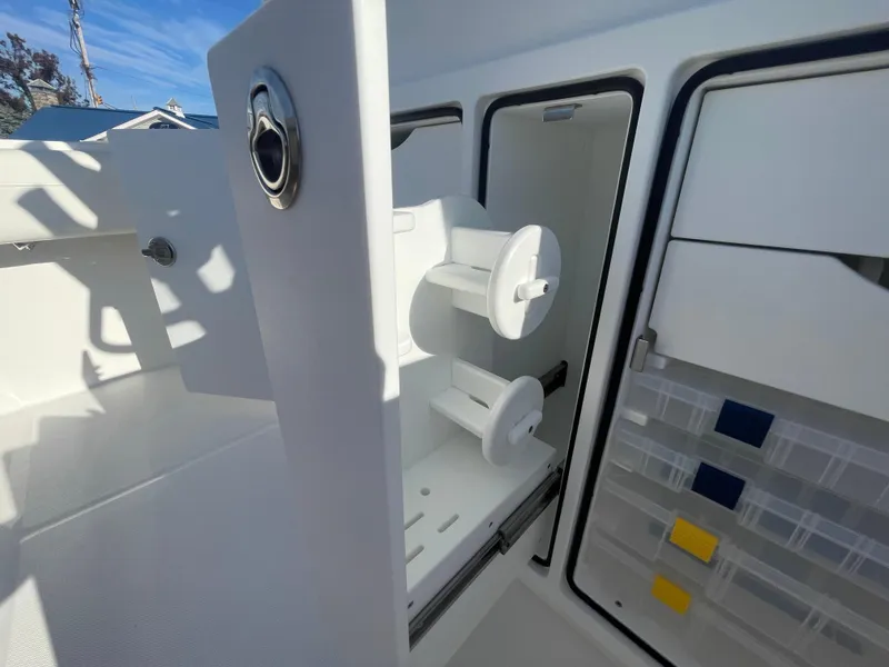 Slide: The Image of 2025 Regulator 28 boat storage compartments with tackle boxes and spool holders. - 38