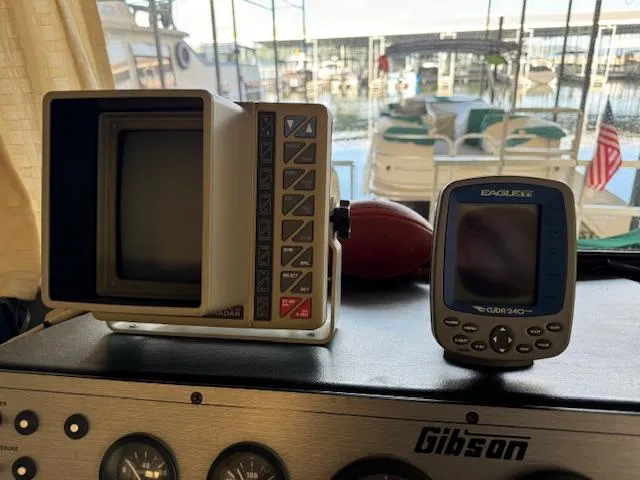 Slide: The Image of Vintage Gibson 44 Standard boat dashboard with radar and GPS devices, marina view in background. - 11