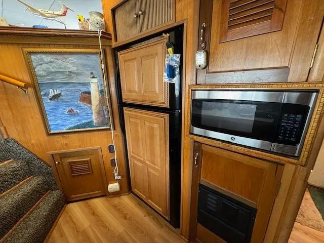 Slide: The Image of Wood-paneled kitchen with microwave, fridge, and nautical painting in a 1994 Gibson 44 Standard. - 29