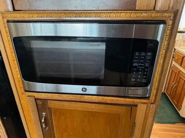 Slide: The Image of Built-in GE microwave with stainless steel finish in a wooden kitchen cabinet. - 30