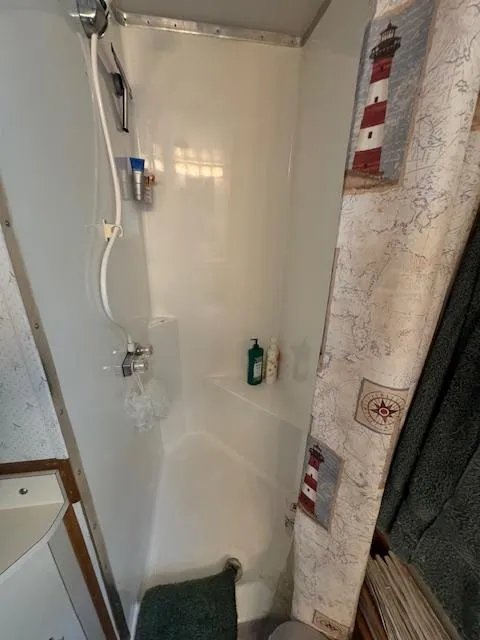 Slide: The Image of Compact shower area with lighthouse-themed curtain in a 1994 Gibson 44 Standard. - 38