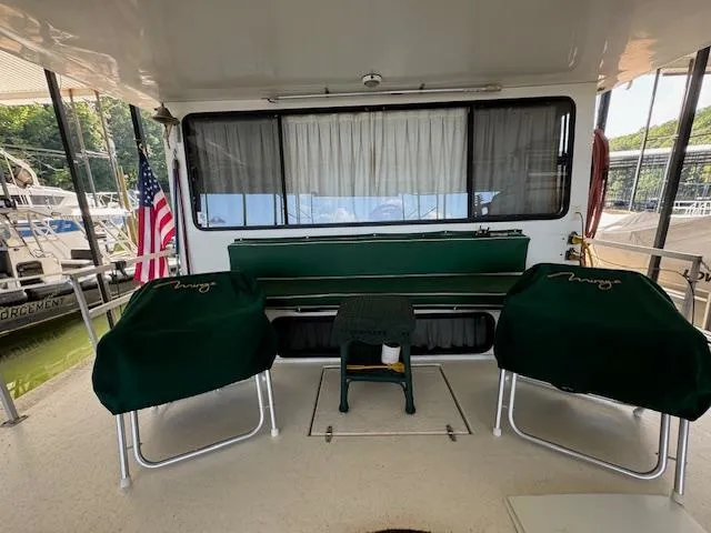 Slide: The Image of 1994 Gibson 44 Standard boat deck with green covered chairs and American flag. - 4