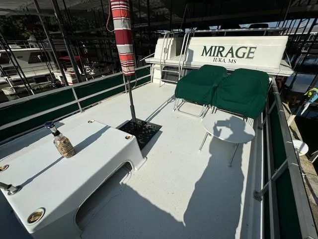 Slide: The Image of 1994 Gibson 44 Standard boat deck with chairs and table, labeled "MIRAGE" in Iuka, MS. - 49