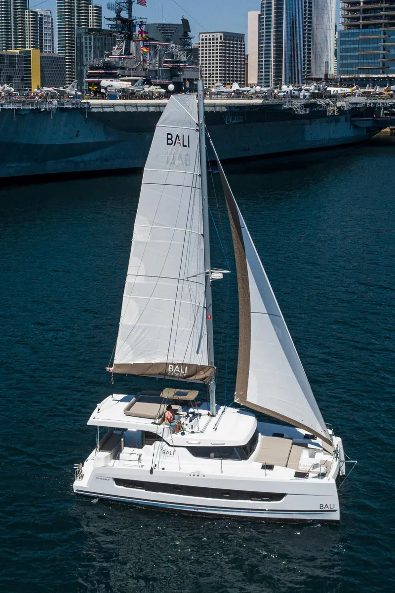 Slide: The Image of 2025 Bali CATSPACE catamaran sailing in a harbor with city skyline background. - 17