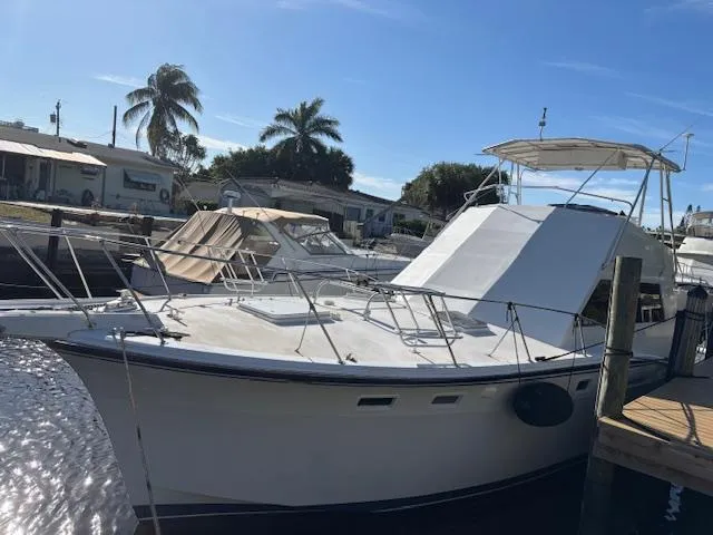The Image of 1976 Hatteras 46 yacht docked, featuring sleek design and spacious deck under clear skies. - 0