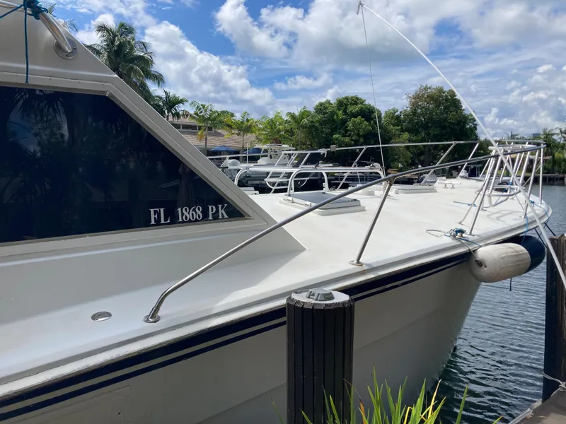 Slide: The Image of 1976 Hatteras 46 yacht docked by a scenic waterfront under a blue sky. - 10