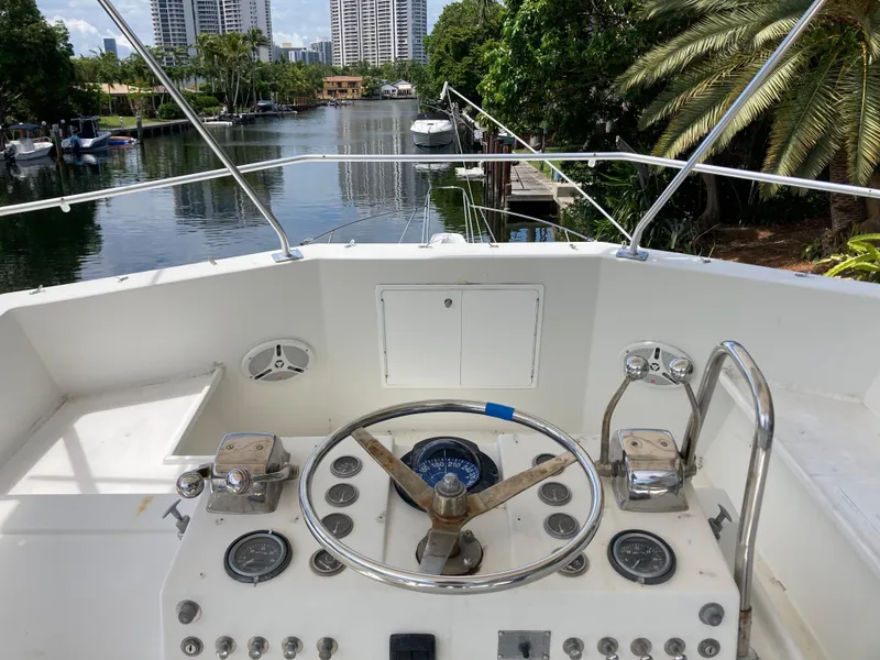 Slide: The Image of 1976 Hatteras 46 yacht helm with scenic waterway and lush greenery. - 17