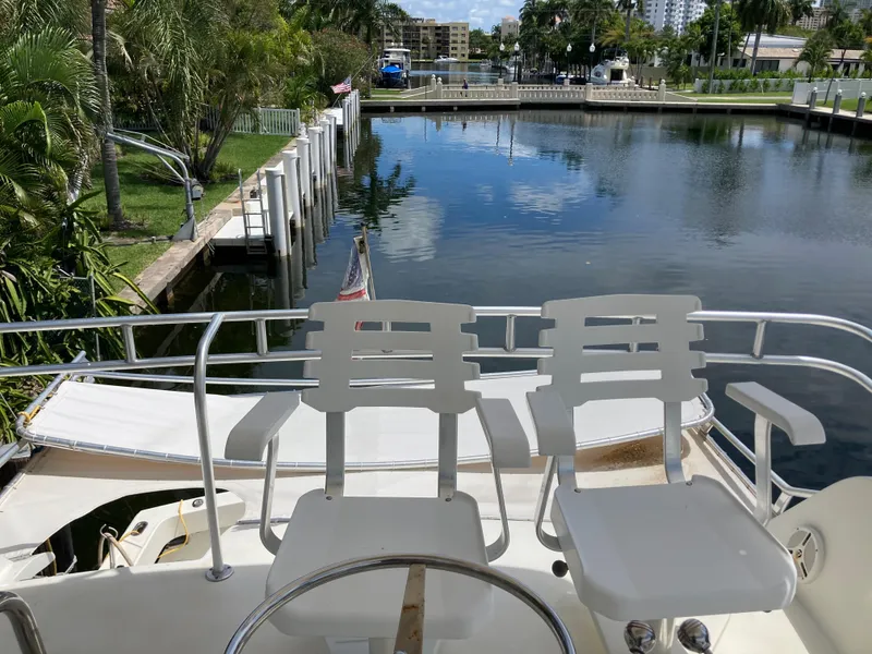 Slide: The Image of 1976 Hatteras 46 yacht with two chairs overlooking a serene marina. - 19