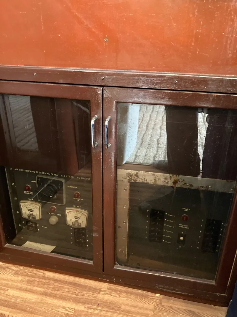 Slide: The Image of 1976 Hatteras 46 electrical panel with wooden cabinet and glass doors. - 30