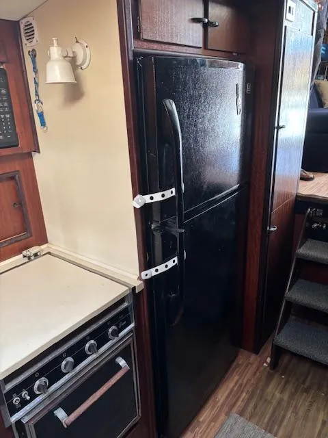 Slide: The Image of 1976 Hatteras 46 yacht kitchen with black fridge and stove. - 36