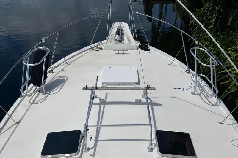 Slide: The Image of 1976 Hatteras 46 yacht deck with railing and hatches, docked by calm water. - 4