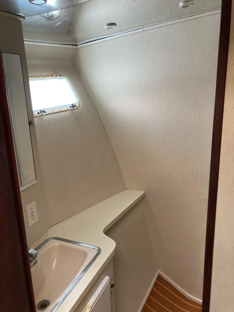 Slide: The Image of 1976 Hatteras 46 yacht bathroom with sink, mirror, and porthole window. - 41