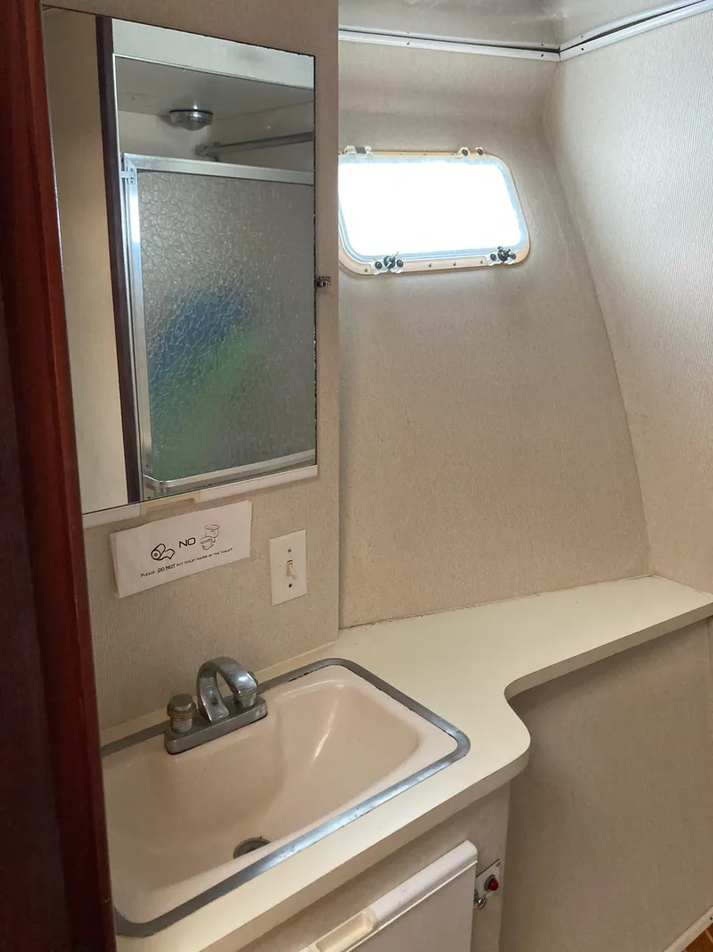 Slide: The Image of 1976 Hatteras 46 yacht bathroom with sink, mirror, and porthole window. - 42