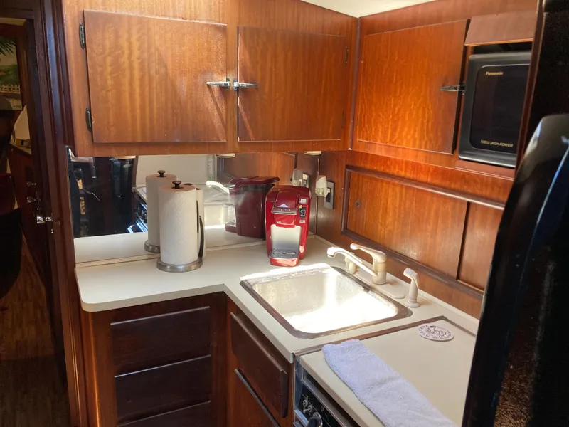 Slide: The Image of 1976 Hatteras 46 yacht kitchen with wooden cabinets, sink, and red coffee maker. - 43