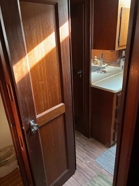 Slide: The Image of 1976 Hatteras 46 interior with wooden door, kitchenette, and natural light. - 47