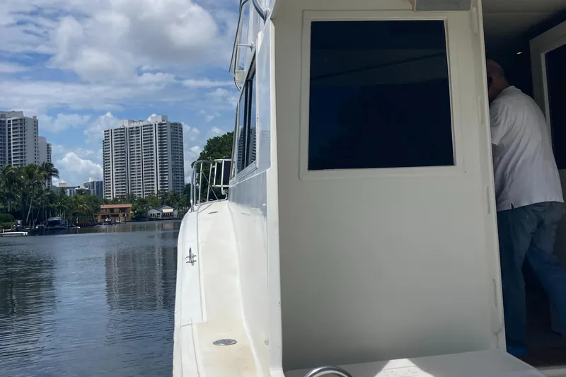 Slide: The Image of 1976 Hatteras 46 yacht docked by waterfront with city skyline in background. - 54