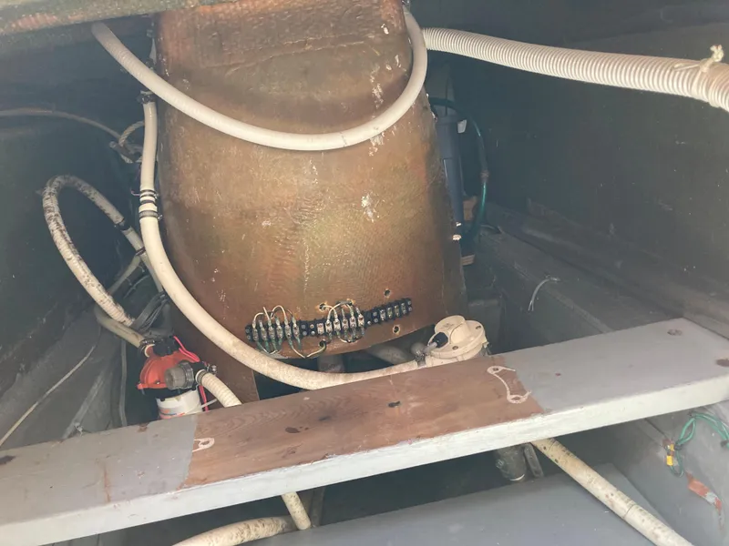 Slide: The Image of Engine room of 1976 Hatteras 46 boat with visible pipes and wiring. - 65