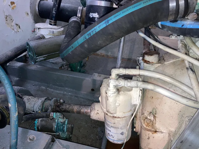 Slide: The Image of Engine compartment of a 1976 Hatteras 46 boat, showing hoses and mechanical components. - 67