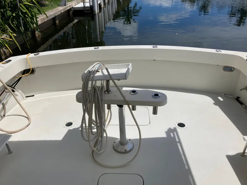 Slide: The Image of 1976 Hatteras 46 boat deck with fishing rod holders by a calm waterfront. - 7