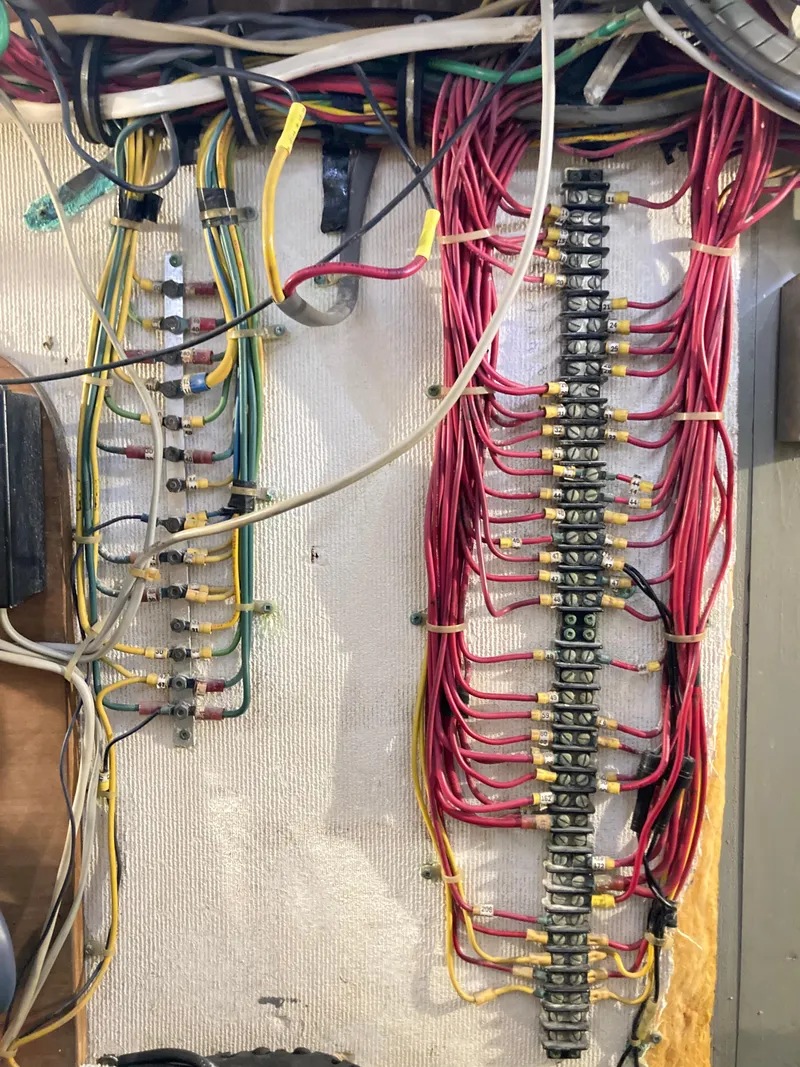 Slide: The Image of Electrical wiring panel in a 1976 Hatteras 46 boat, featuring organized red and yellow cables. - 73