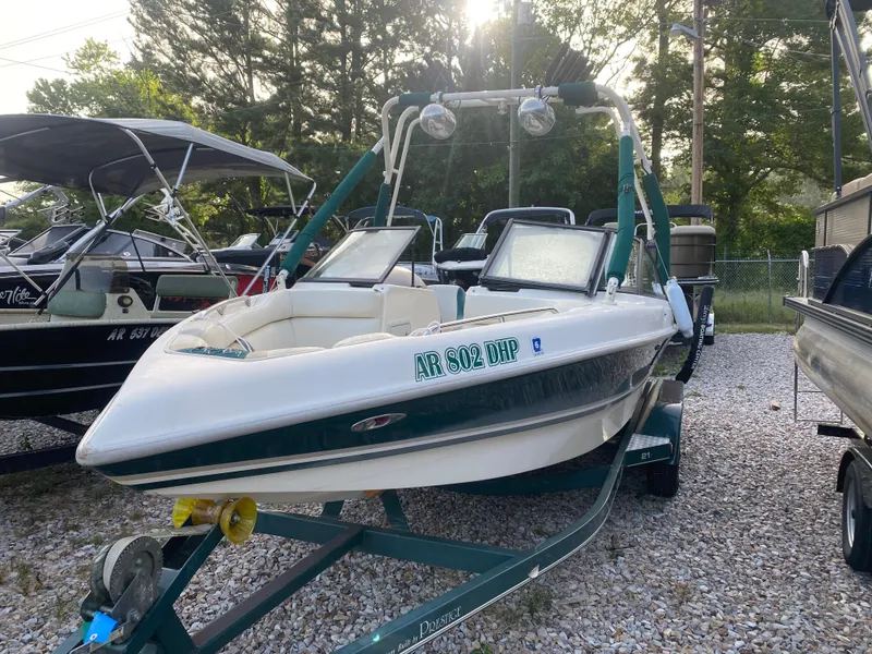 Slide: The Image of 2001 Tigé 211 boat on trailer, parked outdoors, surrounded by trees and other boats. - 0