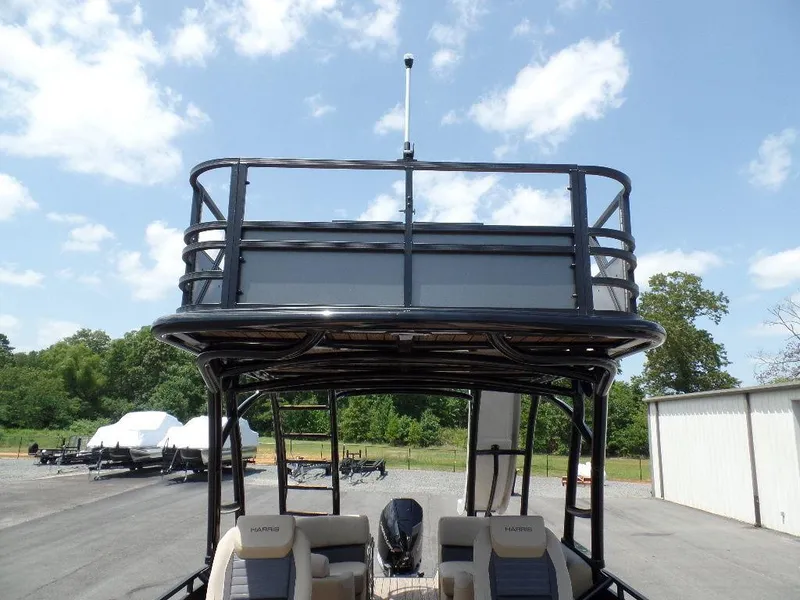 Slide: The Image of 2025 Harris Solstice 270 REC boat with upper deck, parked outdoors under a clear sky. - 16