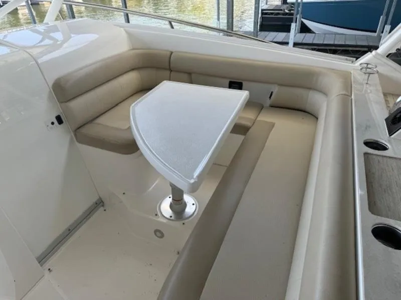 Slide: The Image of 2016 Everglades 360LXC boat interior with beige seating and a small table. - 20