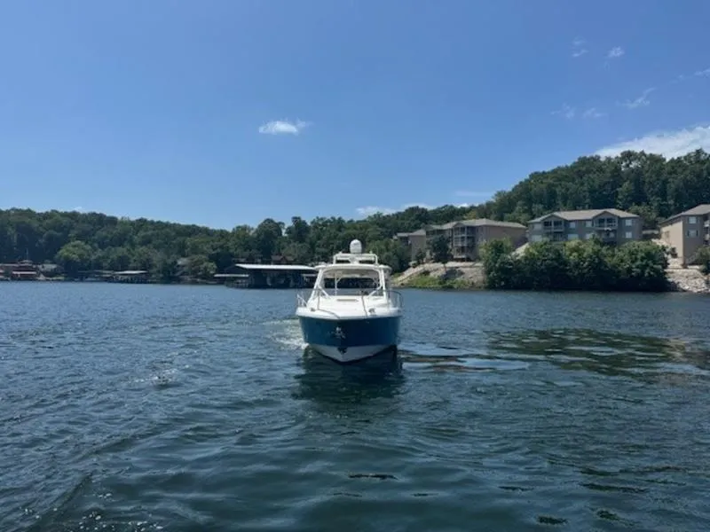 Slide: The Image of Everglades 360LXC 2016 boat on a scenic lake with houses in the background. - 29