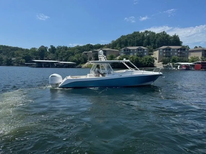 Slide: The Image of 2016 Everglades 360LXC boat cruising on a scenic lake with waterfront homes. - 35