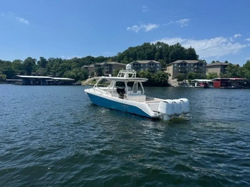 Slide: The Image of 2016 Everglades 360LXC boat cruising on a scenic lake with waterfront homes. - 40