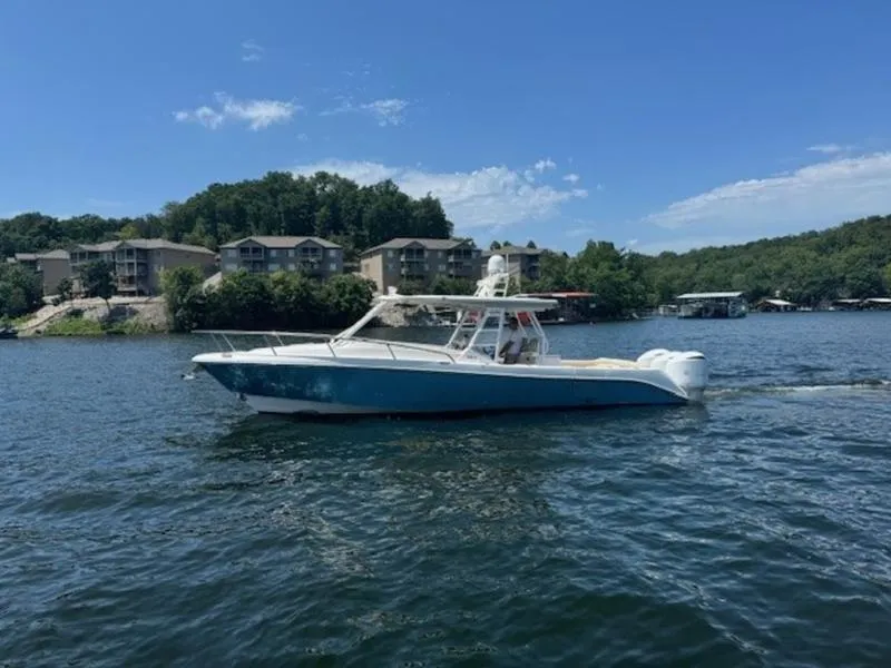 Slide: The Image of 2016 Everglades 360LXC boat cruising on a scenic lake with waterfront homes. - 43