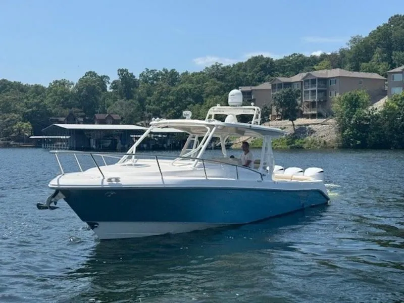 Slide: The Image of 2016 Everglades 360LXC boat on a lake with shoreline and buildings in the background. - 49